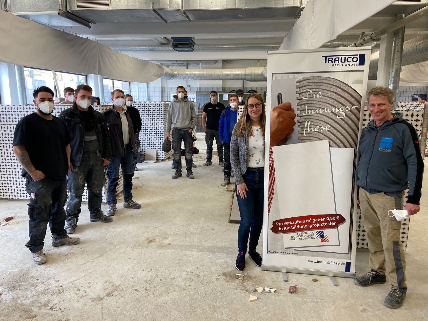 Anja Sjuts (Trauco Fachhandel Bereich Marketing und Vertrieb) und Stefan Bohlken präsentieren die „Innungsfliese“ in den Arbeitshallen der Auszubildenden im zweiten Lehrjahr in Rostrup.