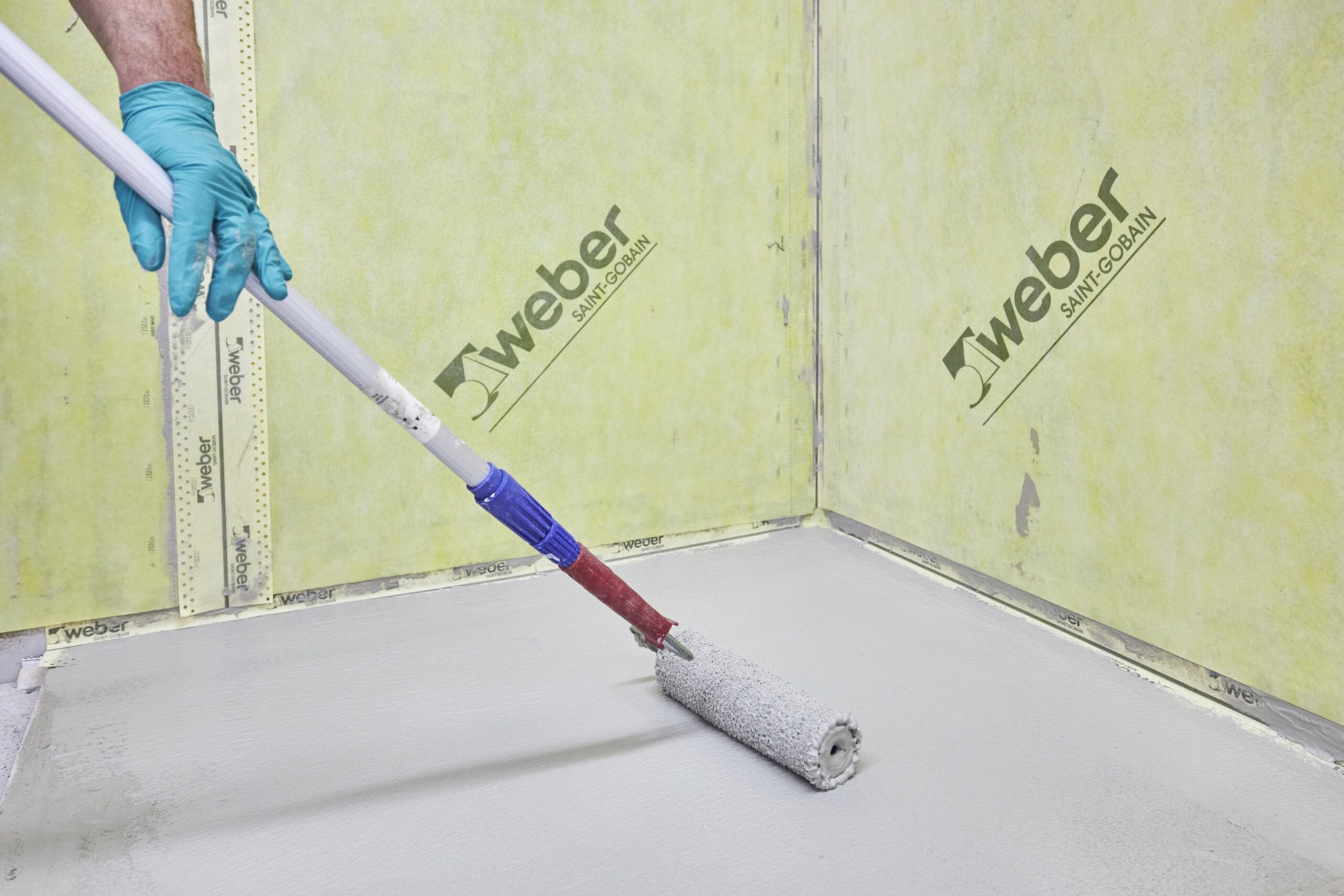 Sowohl an den Wänden als auch am Boden wird der Rollkleber mit der Lammfellrolle aufgetragen. Auch die Stoßbereiche der Dichtbahnen an der Wand können auf diese Weise überarbeitet werden. Foto: Saint-Gobain Weber