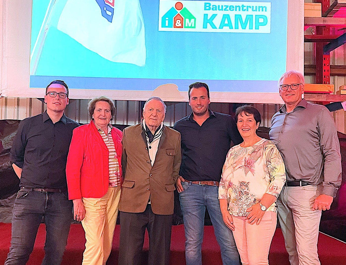 Die Familie Kamp mit dem neuen Logo der i&M-Markengemeinschaft für das Unternehmen im Hintergrund (v. l.): Kai Kamp, Christel Kamp, Ewald Kamp senior, Patrick Kamp, Birgit Kamp, Ewald Kamp junior. Foto: Kamp