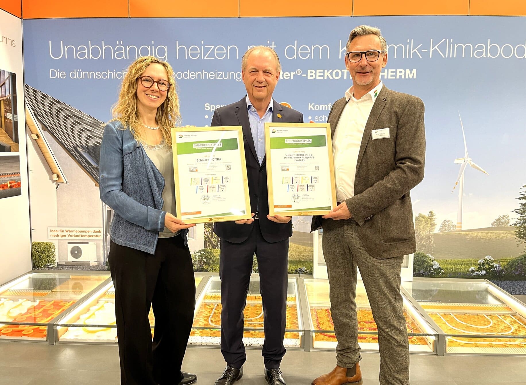 Daniela Schweizer (links) und Ralf Kärger (rechts) vom Sentinel Holding Institut überreichen die Produktpässe an Jörg Hinze, Verkaufsleiter bei Schlüter-Systems.